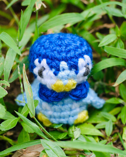 A small blue and white pokemon, similar in shape to a penguin, stand in the grass.